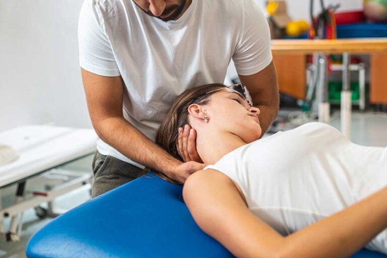 A clinician uses a smooth metal tool on a patient’s forearm during a soft-tissue treatment session.